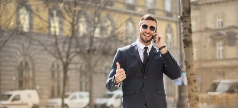 A young businessman giving thumbs up, while using phone to find the best storage units Bronx can offer.