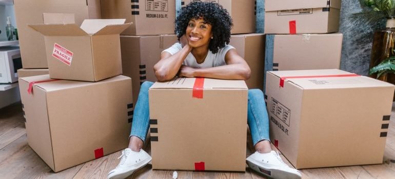 Woman with cardboard boxes - ways items get damaged in storage.