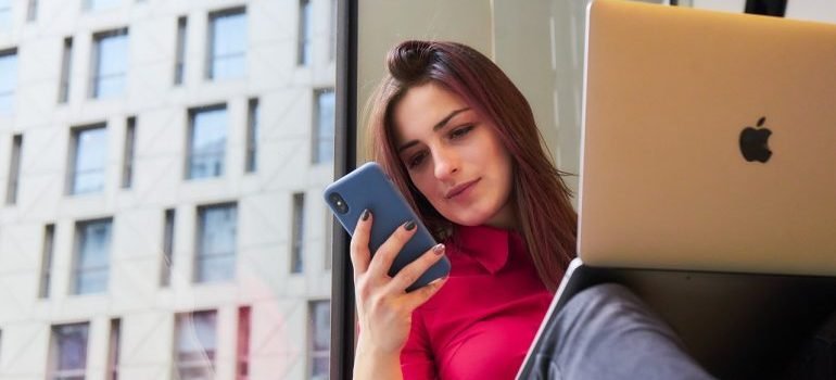 A woman holding a phone and a laptop.