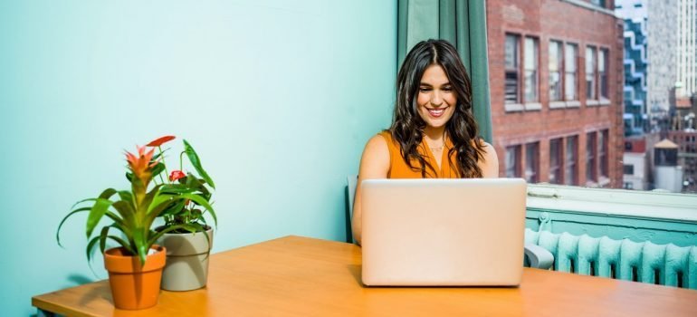 Woman in a blue office using laptop to find commercial storage in NYC
