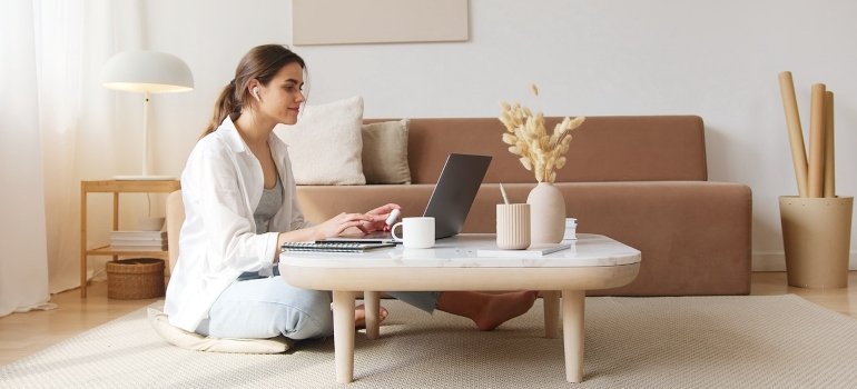 A woman using a laptop on the floor in her studio apartment