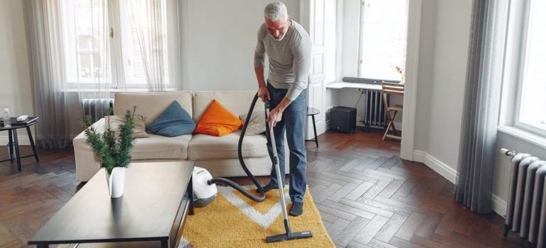 A man vacuuming the carpet in the living room