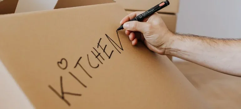A man labelling a box to pack small kitchen appliances