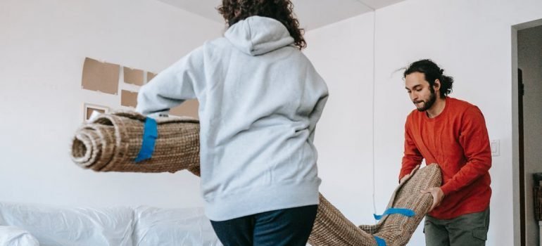 A couple packing their carpet for storage