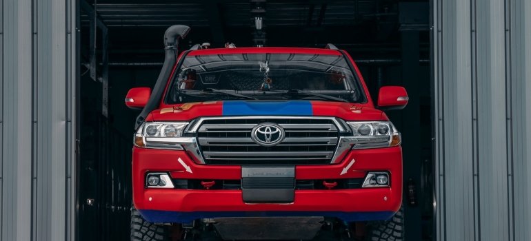 Red and black toyota in front of a storage unit