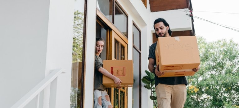 A couple carrying cardboard boxes.