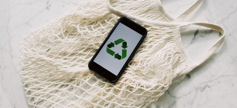 A mobile phone with green recycling sign on a bag