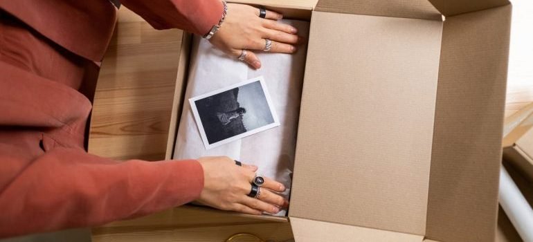 A person packing things in a cardboard box