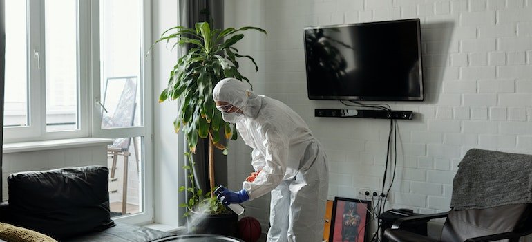 A man in a hazardous suit cleaning living room while thinking how to store furniture in a storage unit;
