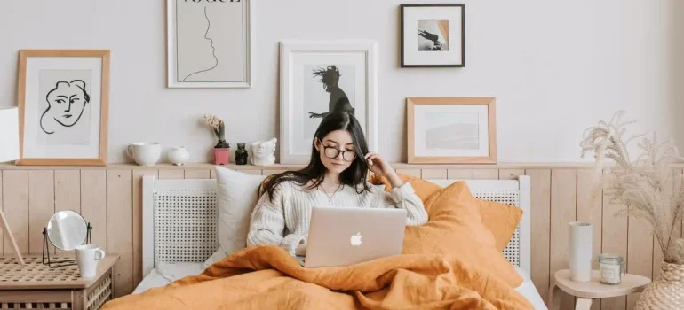 A woman looking at her computer and thinking about what to ask before renting an apartment in New York City