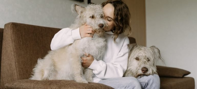 A woman sitting with her dogs on the sofa