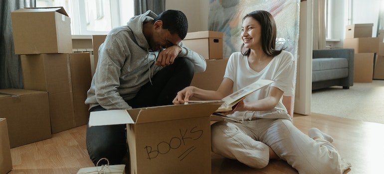 A couple putting books in abox