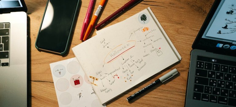 Picture of a laptop, markers and notebooks as some of the college dorm organization musts.