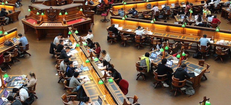 Lots of students sitting in a library.