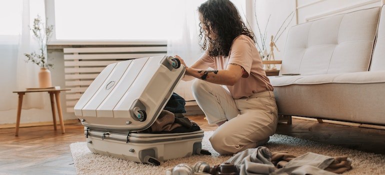 Girl putting her things into a suitcase and following packing tips for students moving in New York.