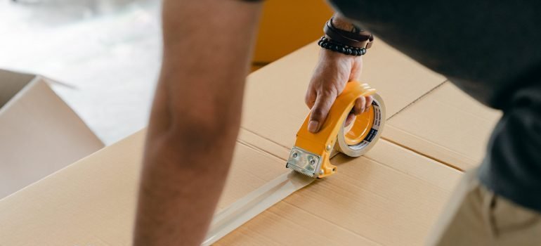 a man sealing a cardboard box