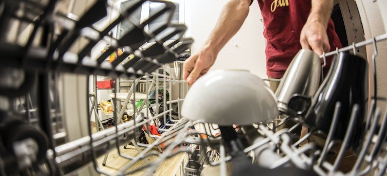 Fish-eye photography of man pulling the dishwasher rack