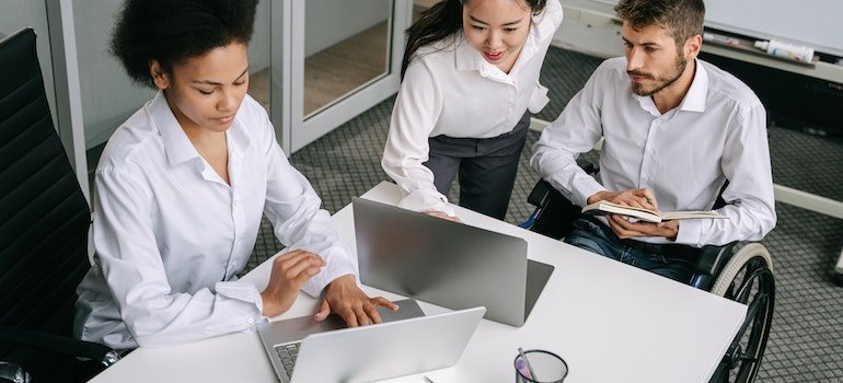 a man and two women looking at laptops