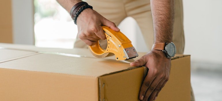 man taping a box for storing fine china items
