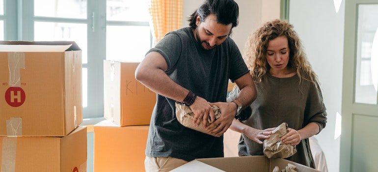 couple packing belongings in parchment near different boxes indoors
