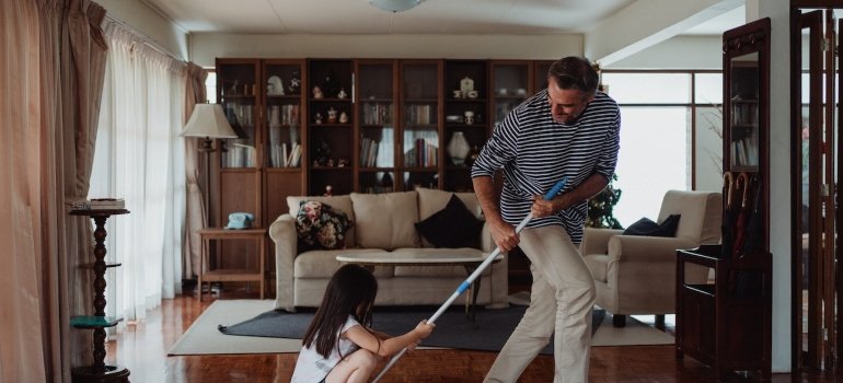 Picture of an adult and a kid having fun while cleaning the floors