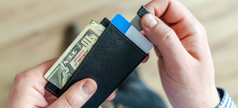 A person holding their wallet and deciding on wheater they want to take cash or a credit card