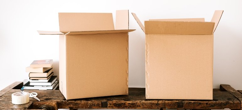 two cardboard boxes on a table with books around