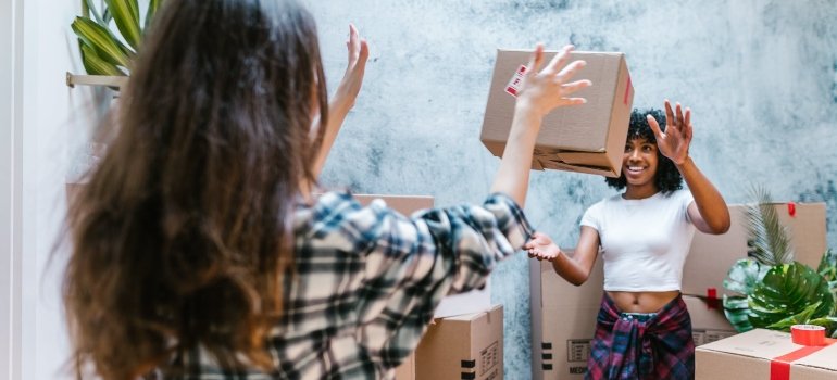 a woman throwing a box to her friend