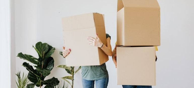 A couple carrying boxes that are covering their heads