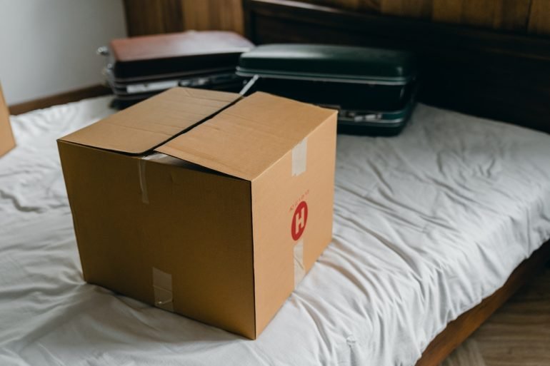 Packing box on the bed with suitcases behind