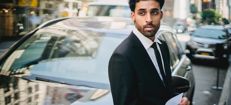A businessman standing in front of his car looking at distance