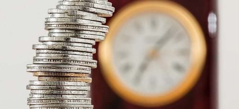 A pile of coins with a clock in the background