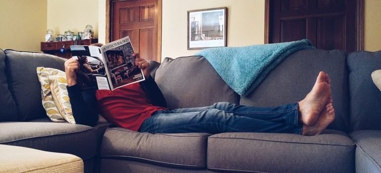 A man laying on the couch reading a magazine