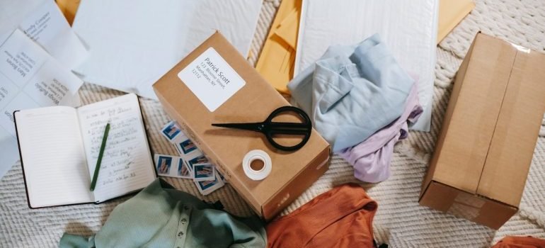 A messy room with boxes, scissors, and clothes