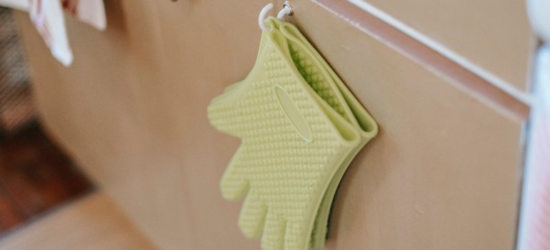 A pair of green, rubber gloves, hung up on the side of the drawer.