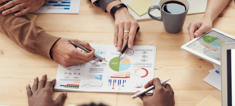 Three people inspecting some charts and graphs