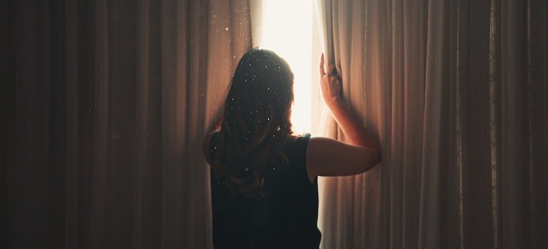 a woman opening heavy curtains