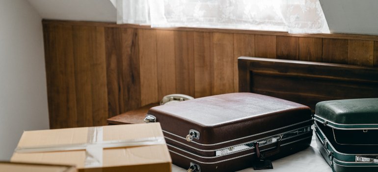 A picture of several suitcases and boxes on the bed.
