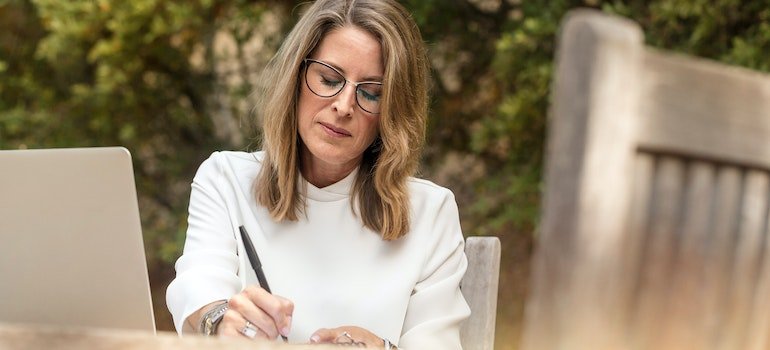 a woman reading and writing on a piece of paper about New York tiny home rules & regulations