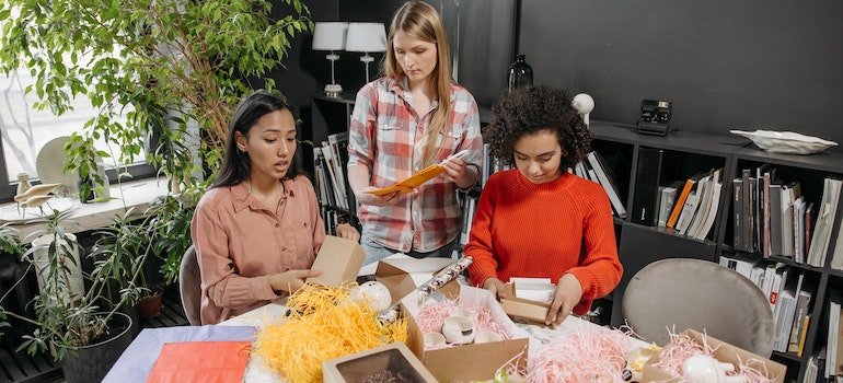 three women packing small boxes at the desk