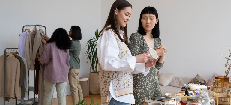 Four women exchanging various items, the practice of which is part of the tips on maximizing your storage space in the Bronx.