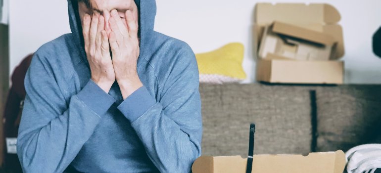 a man crying while sitting in front of several boxes
