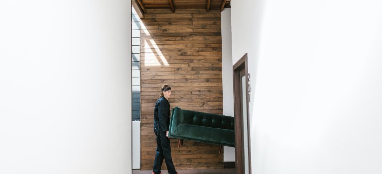 people rearranging a green sofa