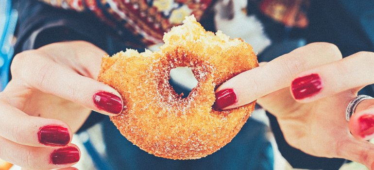 a woman with red nails holding a doughnut