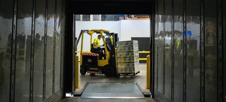 A person transporting boxes using a fork lifter.