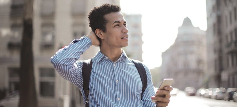 A person in the street using a smartphone and thinking