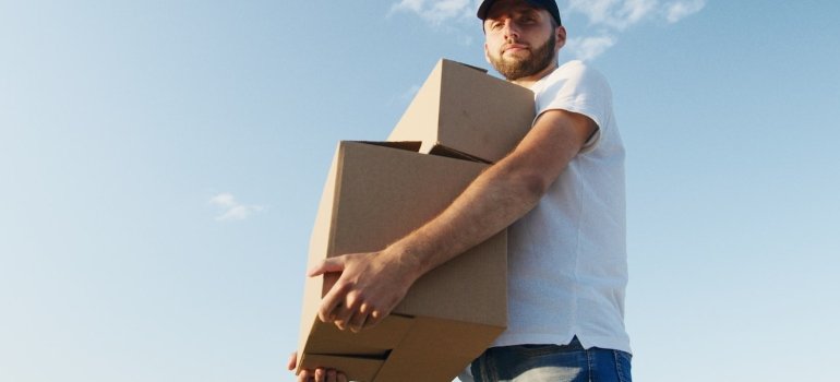 A person carrying boxes of items to be secured in the self storage Parkchester locals praise.