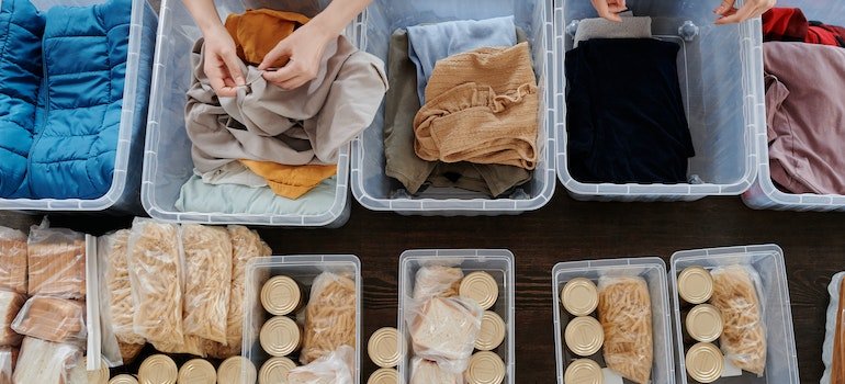 A person sorting items in plastic containers after having decided what to do with sentimental items