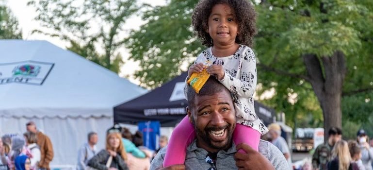 A man carrying his daughter on his shoulders
