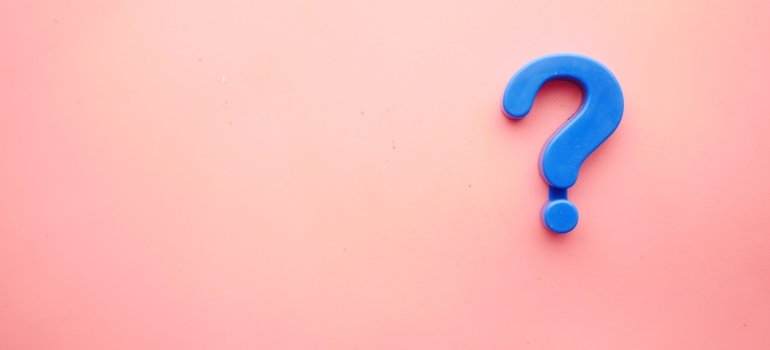A blue question mark on a pink background.